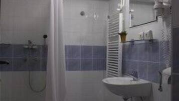 Een badkamer met douche, toilet, wastafel en spiegel.
