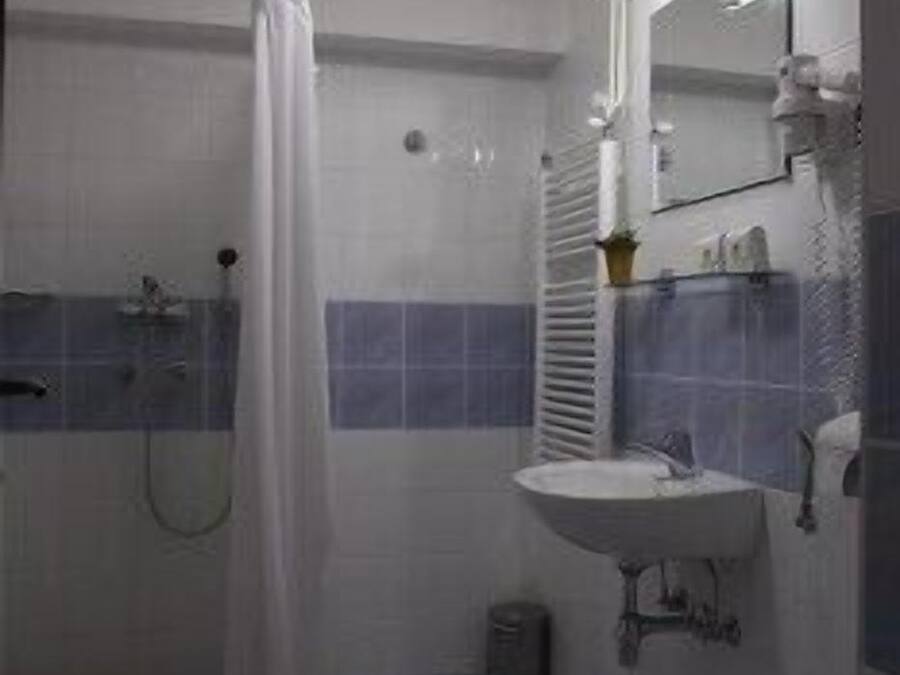 Een badkamer met douche, toilet, wastafel en spiegel.