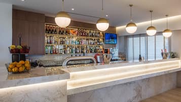 Un área de bar moderna con una encimera de mármol, iluminación colgante y una estantería llena de botellas de vino.