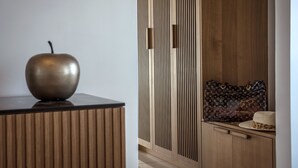 Een modern interieur met een houten kast, een metalen appelschulptuur en een Louis Vuitton handtas op een aanrecht.