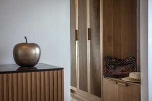 Un intérieur moderne avec un meuble en bois, une sculpture de pomme en métal et un sac à main Louis Vuitton posé sur un comptoir.
