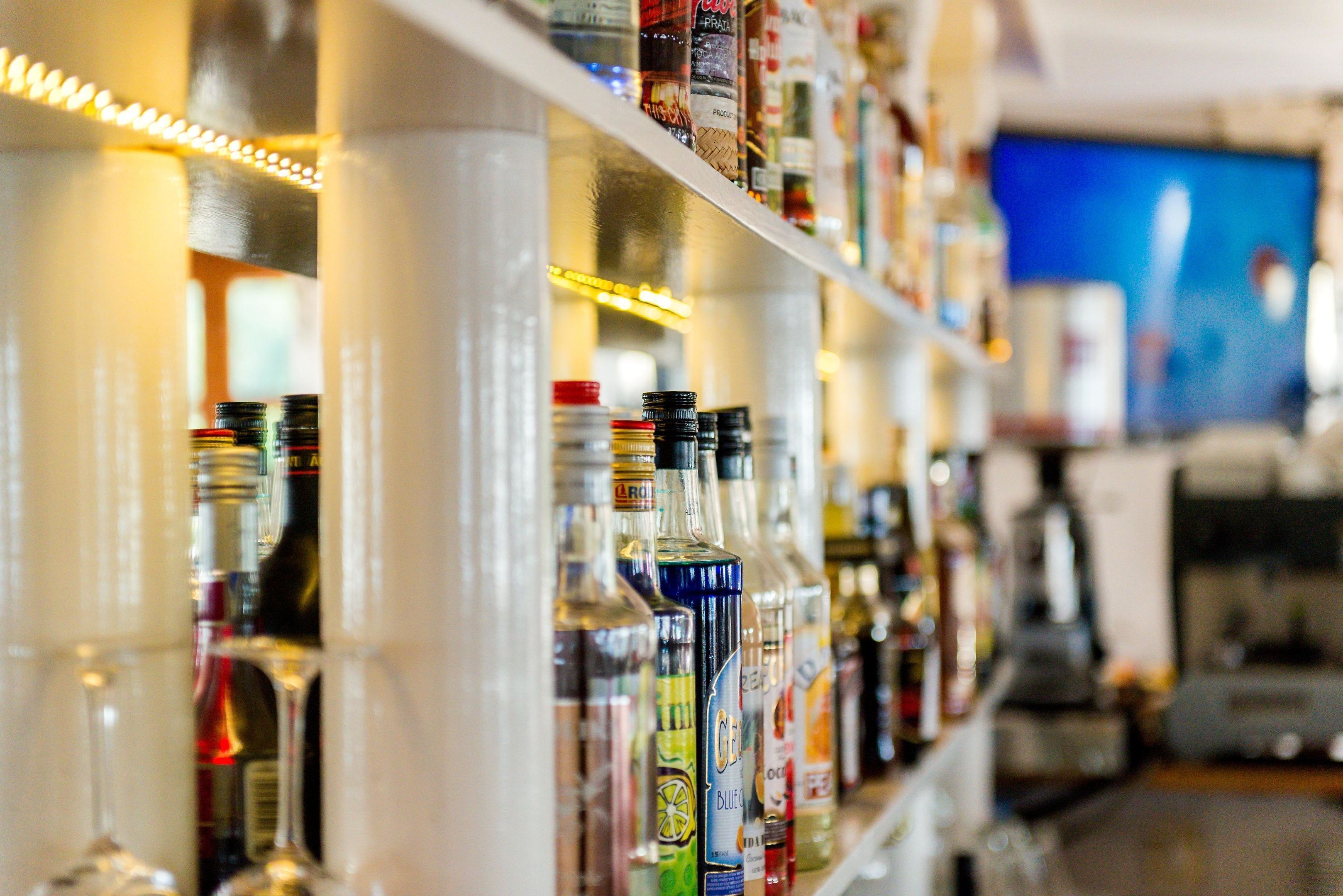 Un bar con estantes llenos de botellas de licores varios.
