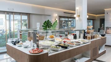 A buffet setup with various food items and a glass barrier.