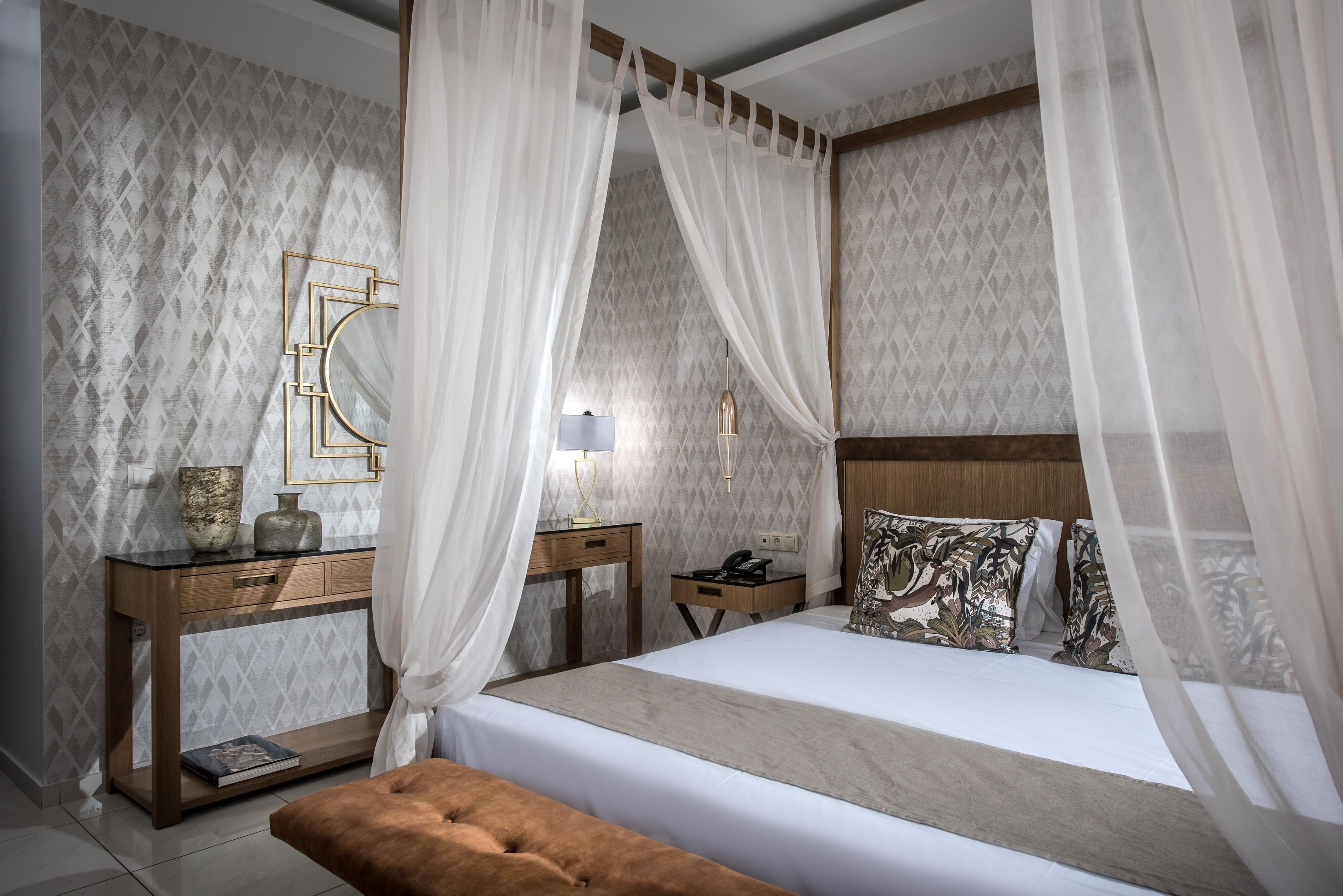 A bedroom with a bed, bedside tables, a nightstand, a lamp, and a decorative mirror.