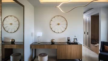A modern hotel lobby with two large wall clocks, a wooden console table with a coffee machine, and a seating area with a chair.