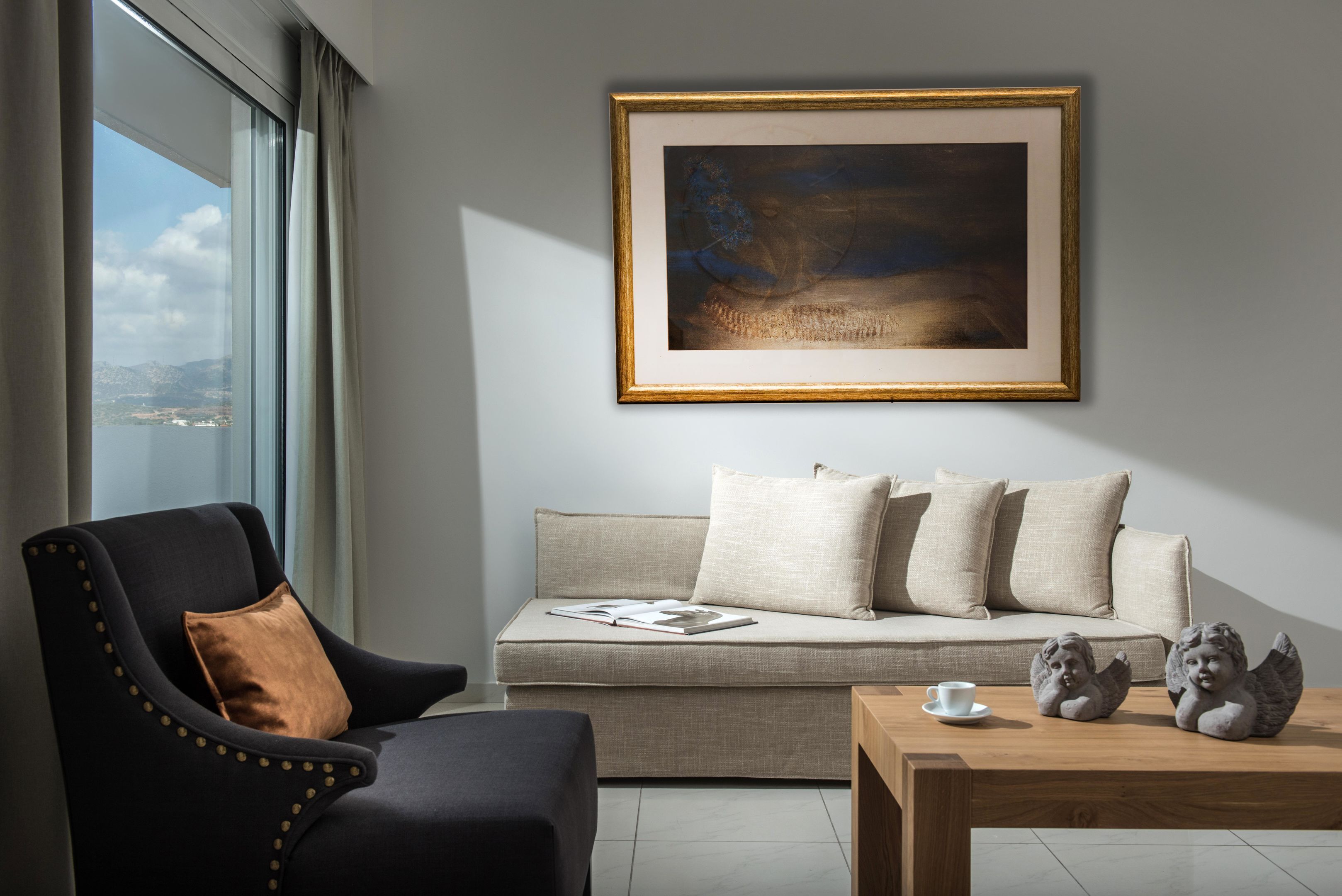 A modern living room with a sofa, armchair, and coffee table, featuring a framed artwork above the sofa.