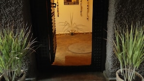 A doorway with a textured wall and a small window. There are two potted plants on either side of the doorway. - Riad Nomades (Marrakech)