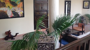 A lobby with a wooden door, a large painting, and a staircase with a railing. - Riad Nomades (Marrakech)