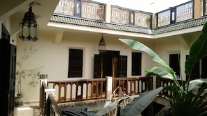 A courtyard with a wooden balcony, a hanging lantern, and potted plants. - Riad Nomades (Marrakech)