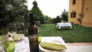 An outdoor dining setup with a table set for two, featuring a bottle of wine, wine glasses, and cutlery. - Agriturismo Borgo delle Vigne (Zola Predosa)