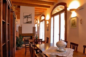 Un comedor con muebles de madera, chimenea y ventanas amplias con arcos.