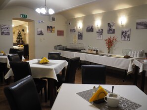A dining area with tables set for meals, a Christmas tree, and wall-mounted photographs. - Résidence Tournet (Kraków)