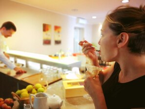 A person eating at a table with a bowl and a spoon. There are fruits and a pitcher on the table. - Hotel San Martino (Syracuse)