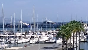 A marina with numerous boats docked, a large yacht in the background, and palm trees in the foreground. - I Mastrazzi B & B (Riposto)