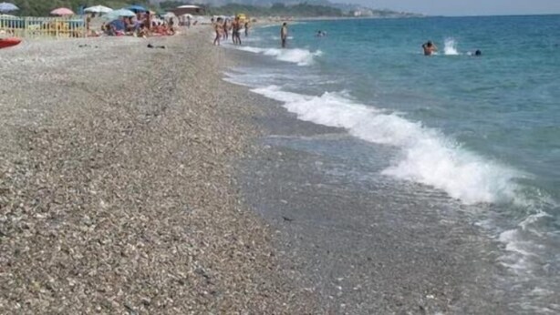 A pebbled beach with umbrellas and people in the water. - I Mastrazzi B & B (Riposto)