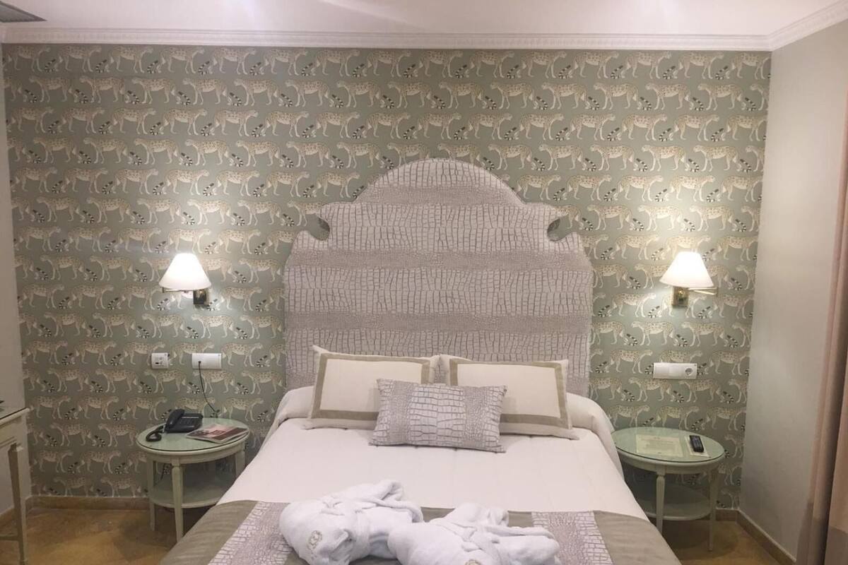 Une chambre d’hôtel avec un lit, deux tables de chevet, une lampe et une serviette sur le lit.