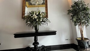 Un amplio pasillo con un gran espejo, un candelabro y una planta en maceta.