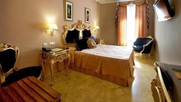 Habitación de hotel con una cama grande, dos mesitas de noche, un escritorio, una silla y una televisión.