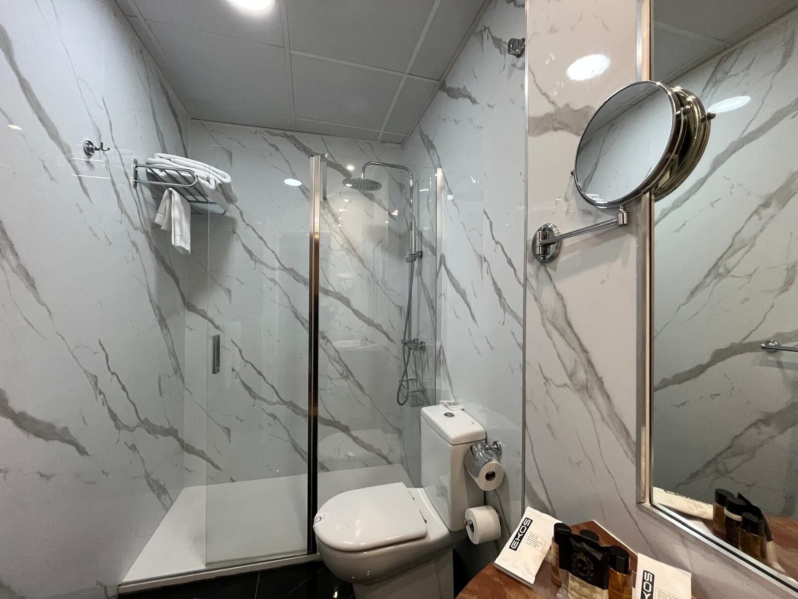 Un baño con inodoro, ducha y espejo.