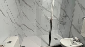 A bathroom with a toilet, bidet, and glass-enclosed shower.
