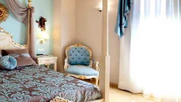 A bedroom with a large bed, a chair, a nightstand, and a wall-mounted light fixture.