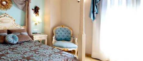 Un dormitorio con una cama grande, una silla, una mesita de noche y una lámpara fijada a la pared.