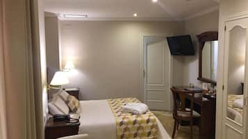 Una habitación de hotel con cama, escritorio, silla, televisor y armario.