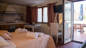 Une chambre d’hôtel comprenant un lit, un bureau, une chaise, une télévision et une porte-fenêtre coulissante donnant sur un balcon.