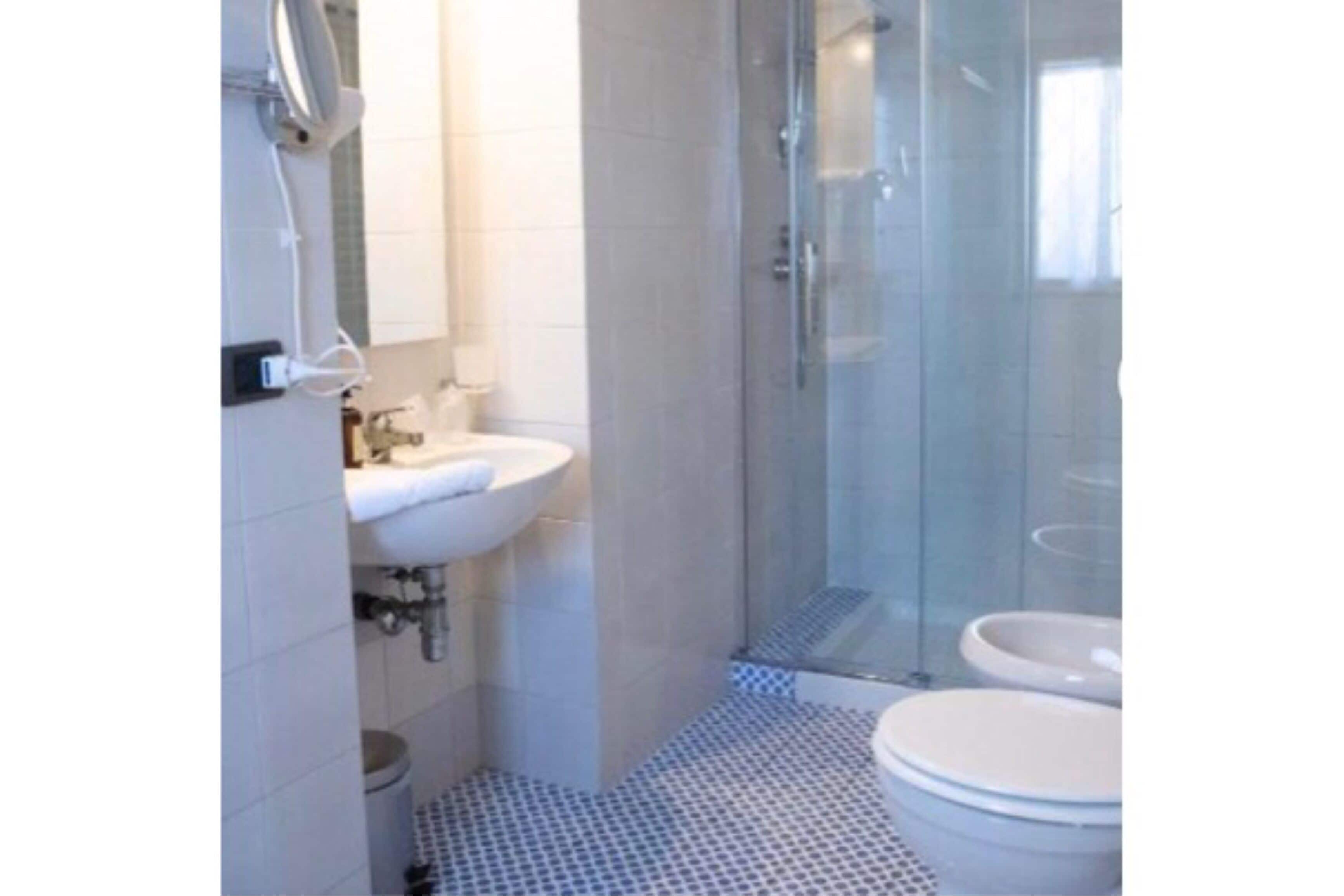 Une salle de bain avec une douche à parois de verre, un lavabo et des toilettes.