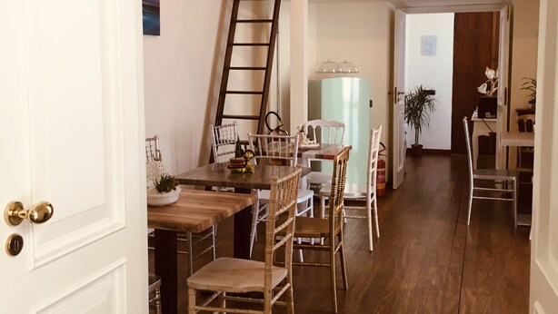 Un coin repas avec une table et des chaises en bois, une échelle et une bibliothèque en arrière-plan.