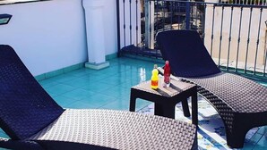 Une terrasse sur le toit avec deux chaises longues, une petite table et une bouteille d’eau.