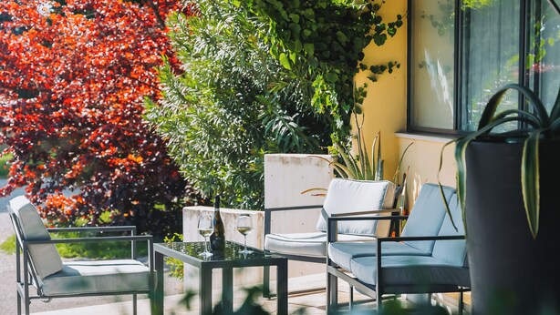 Un patio con dos sillas, una mesa y una botella de vino.