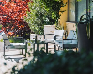 A patio with two chairs, a table, and a bottle of wine. - Hotel all'Oasi (Paese)