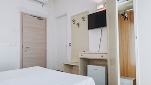 Un dormitorio con cama, escritorio, televisor y armario.