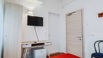 Un dormitorio con cama, escritorio, televisor, aire acondicionado y armario.