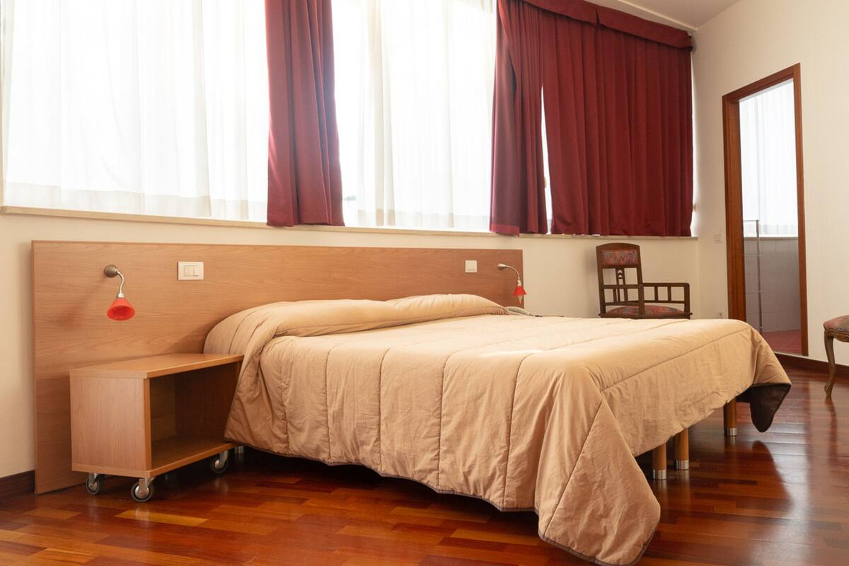 A bedroom with a bed, a desk, and a chair.
