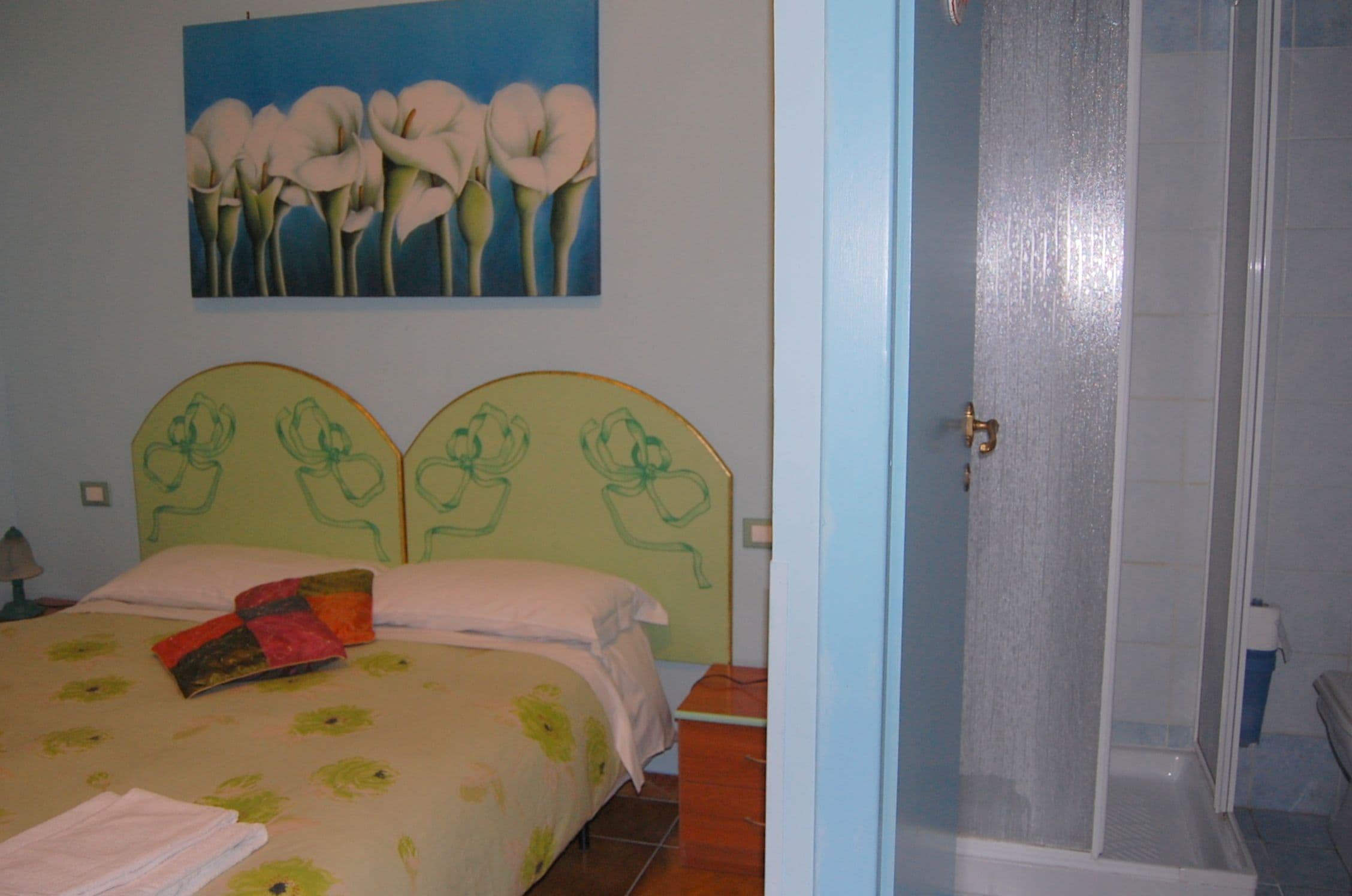 Un dormitorio con cama, ducha y un cuadro en la pared.