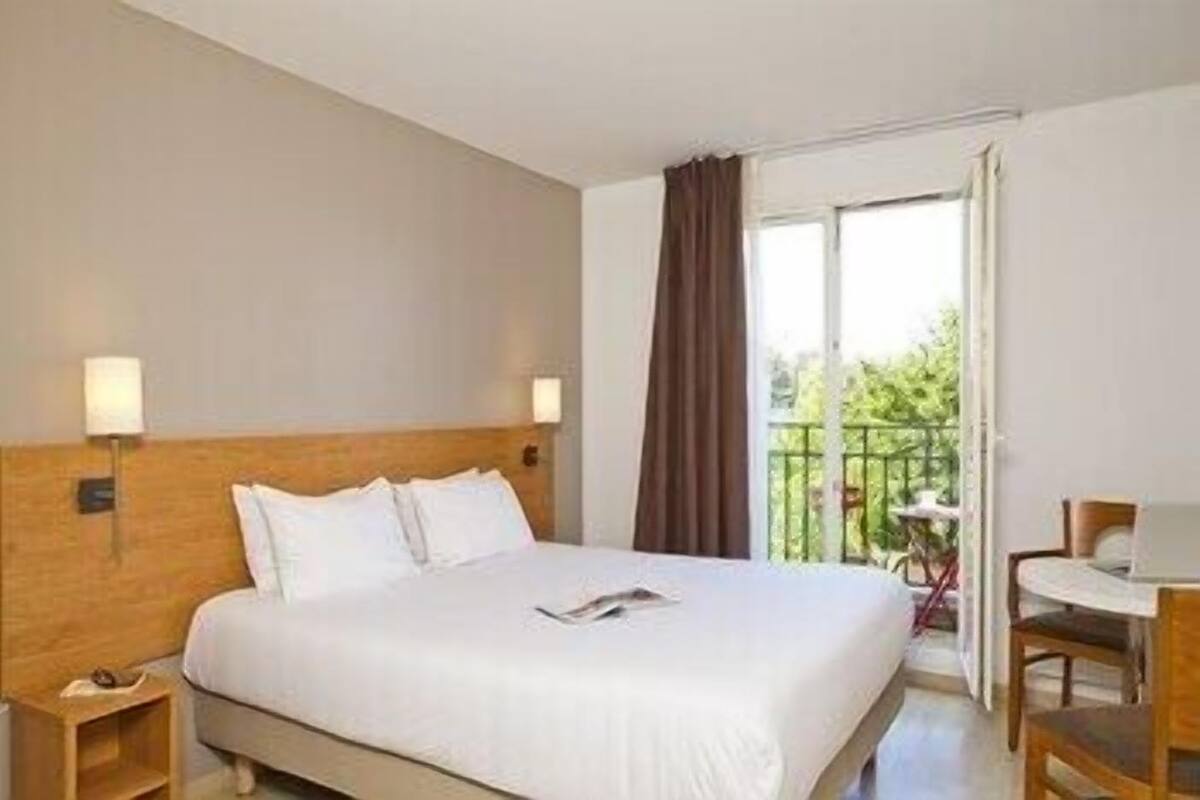 Ein Hotelzimmer mit Bett, Nachttischen, einem Schreibtisch und einem Balkon mit Blick.