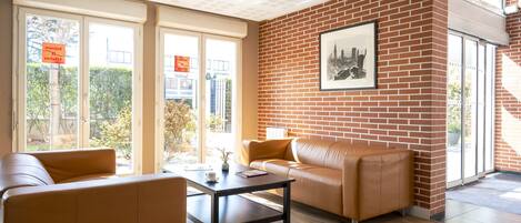 A modern interior with a brick wall, leather sofas, a coffee table, and large windows.