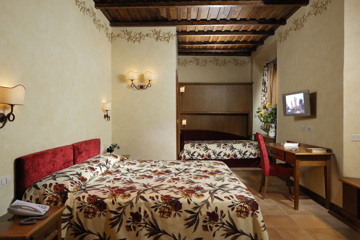 A hotel room with a bed, a desk, a chair, a television, and a telephone.