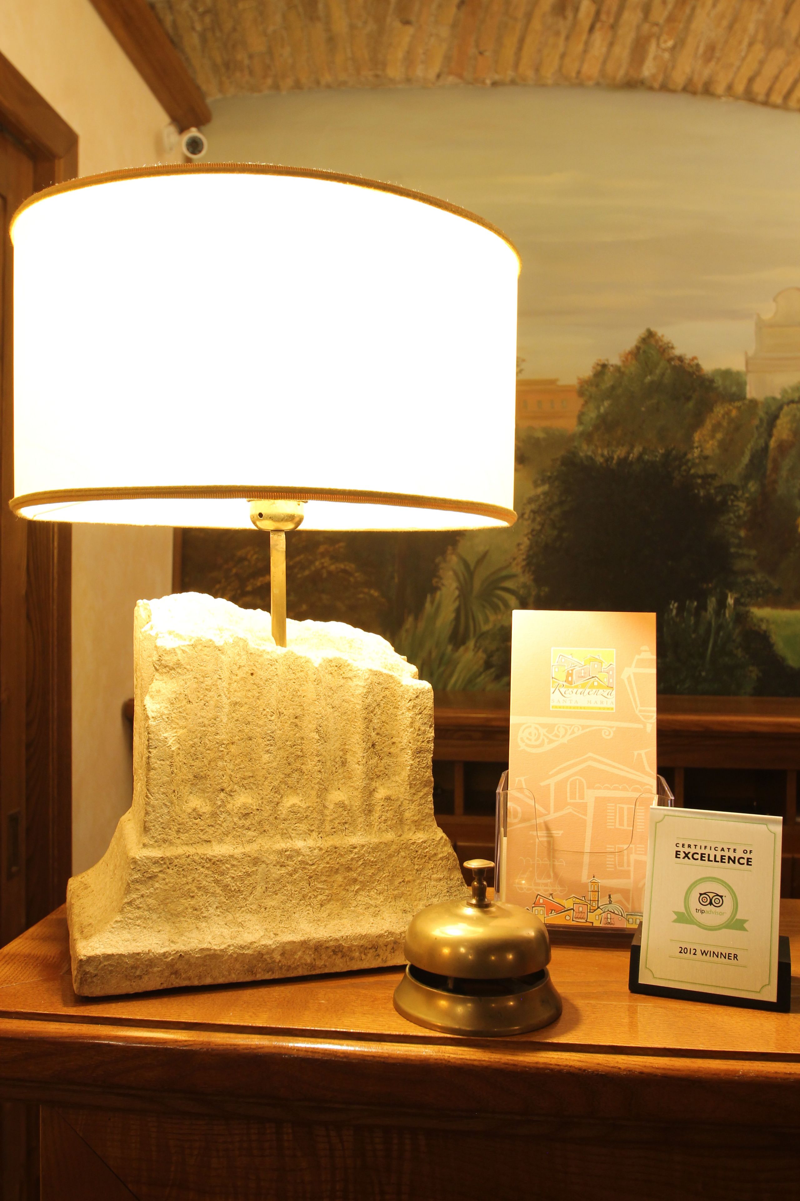 A reception desk with a lamp, a framed certificate of excellence, and a wooden counter.