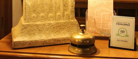 A reception desk with a lamp, a framed certificate of excellence, and a wooden counter.