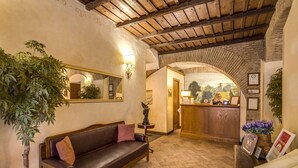 A cozy lobby with a wooden bench, a reception desk, and a large mirror. - Residenza San Calisto (Rome)