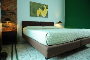 Una camera da letto con un letto, due lampade sui comodini, una parete in mattoni, una parete verde e un quadro.