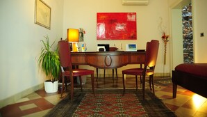 A dining area with a wooden table, two red chairs, a potted plant, and a red abstract painting on the wall. - Sangiuliano 114 (Catania)