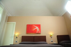 Una camera d'albergo con un letto, due comodini, un'opera d'arte appesa al muro e due applique.
