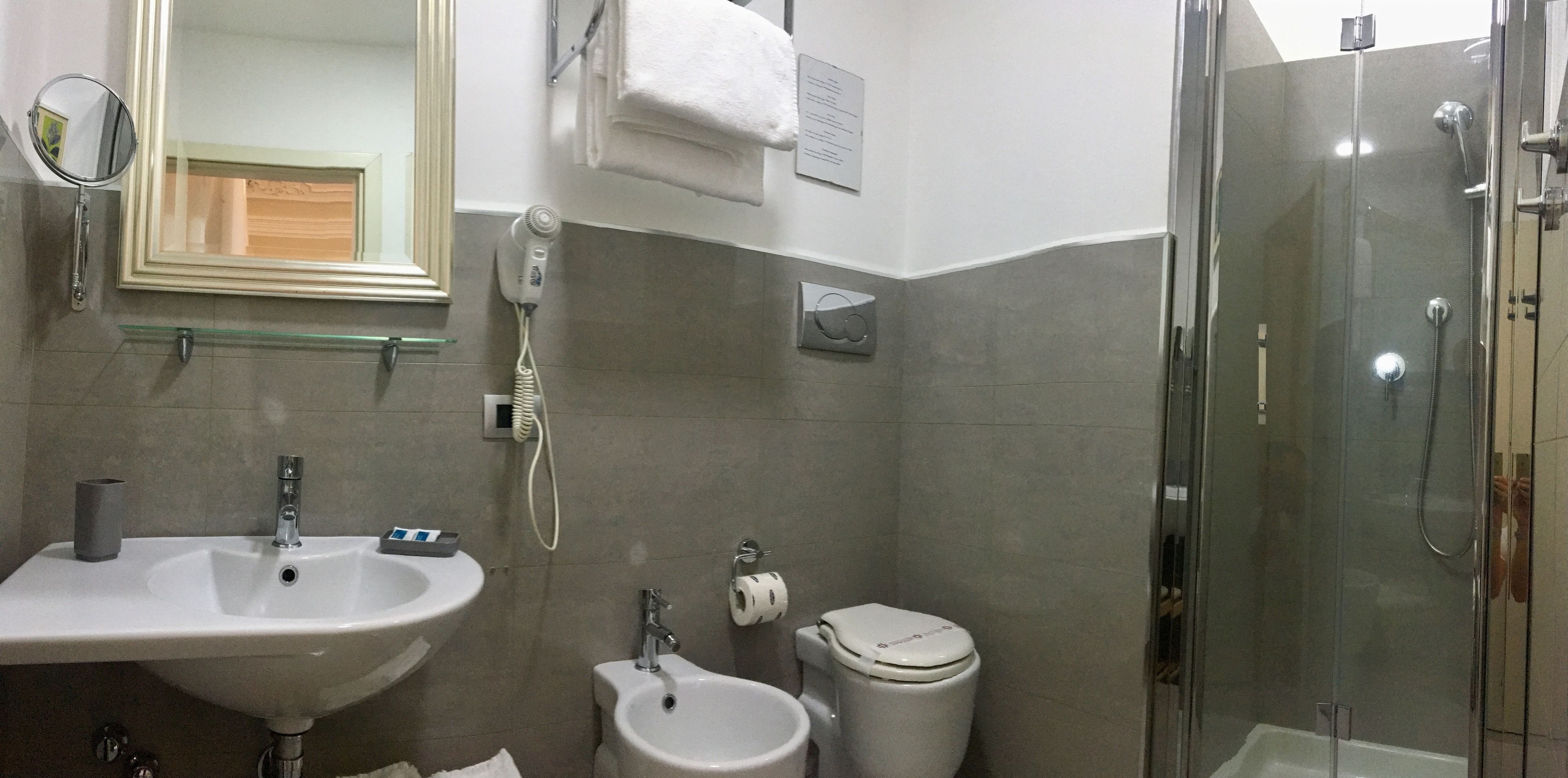 Un baño con lavamanos, bidé, inodoro y ducha con mampara de vidrio.