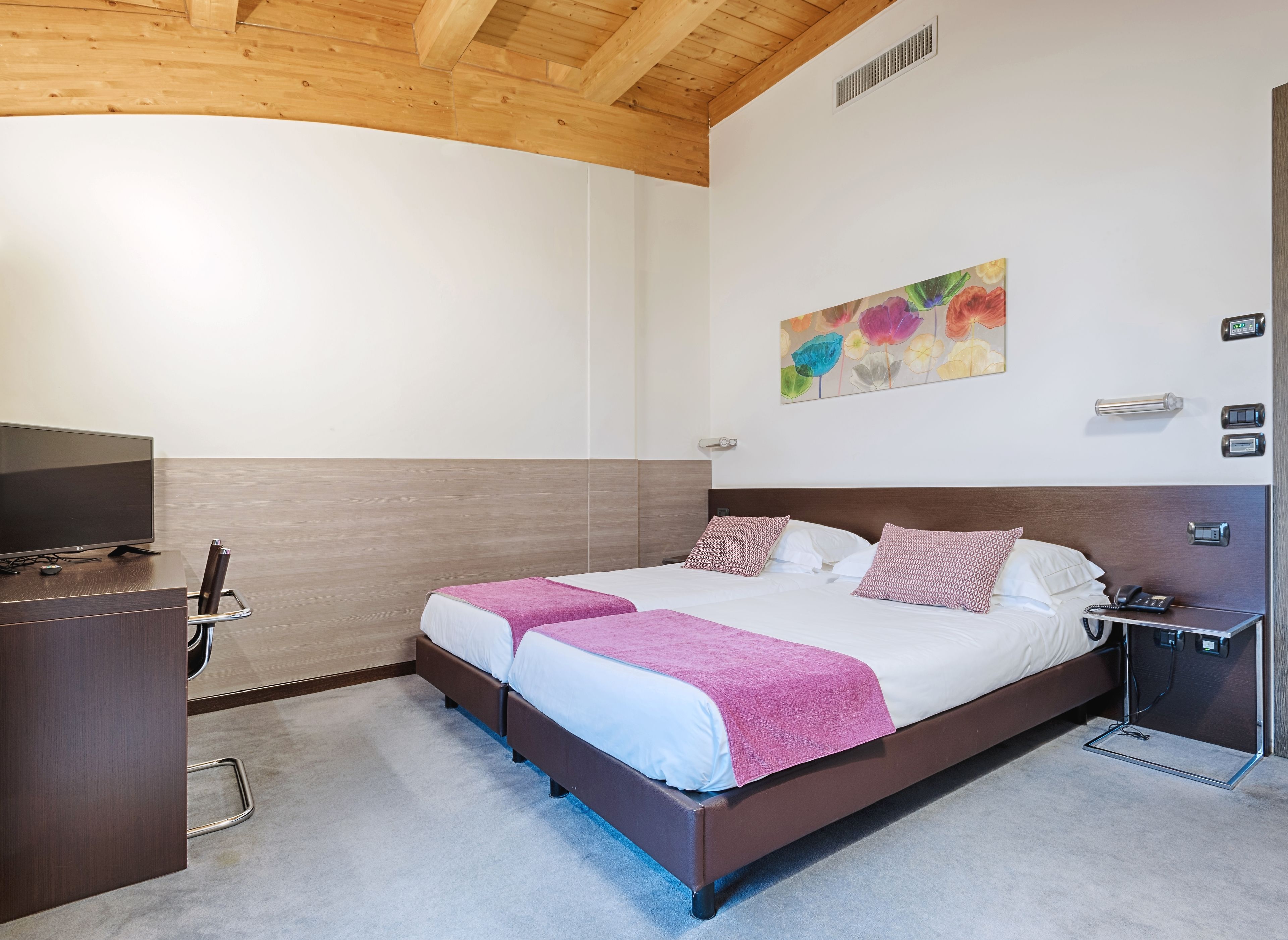 Ein Schlafzimmer mit einem Bett, Nachttischen, einem Fernseher und einem Bild an der Wand.