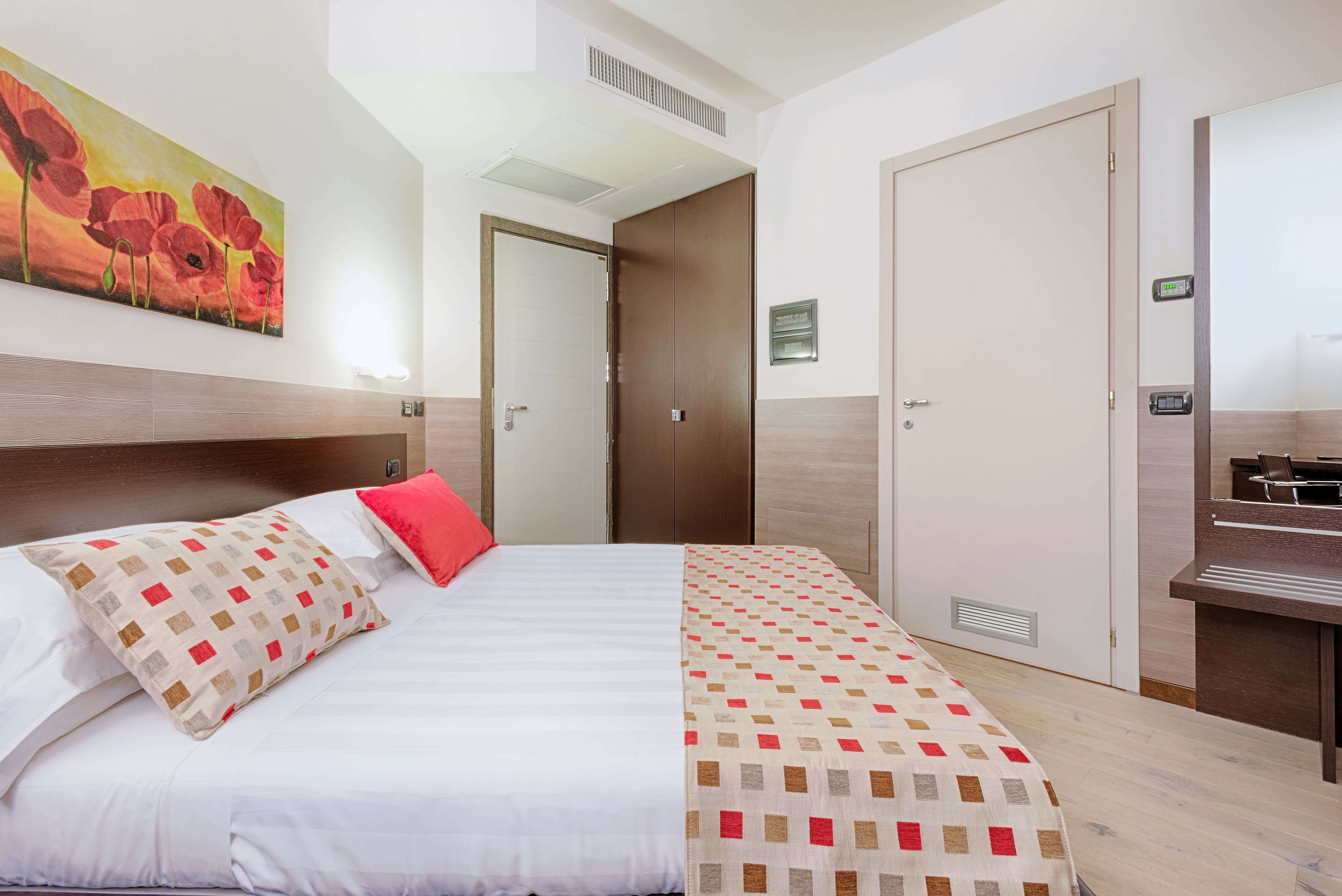 Una habitación de hotel con cama, un cuadro, un escritorio y una puerta.