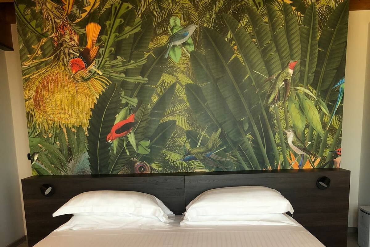 A bed with a headboard featuring a large tropical mural.